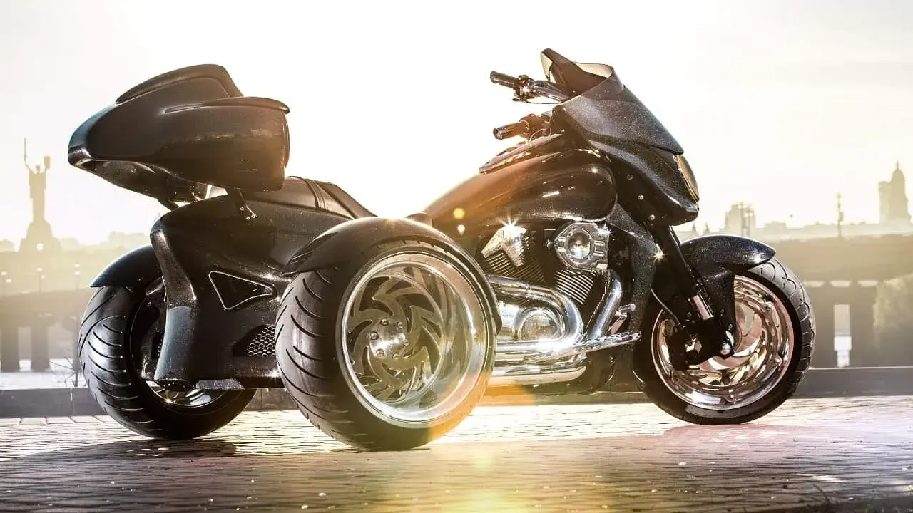 Czarny, lśniący motocykl trójkołowy na kat B. Z imponującymi felgami i sportowym wyglądem, gotowy na podbój dróg.