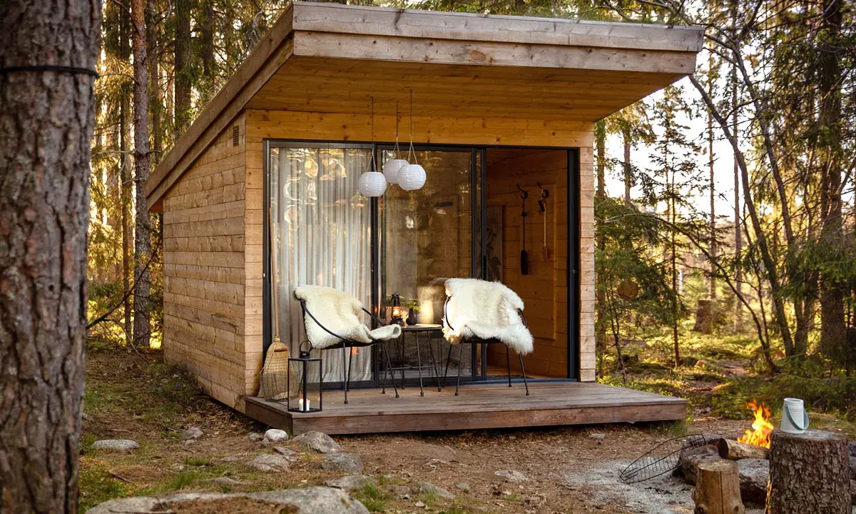 Mysig koja i skogen, perfekt för att bo i som ett skogshotell. Två fårskinnsbeklädda stolar på altanen inbjuder till avkoppling.