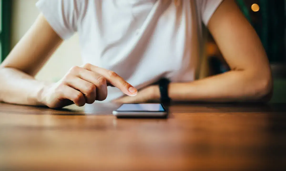 Dłoń dotyka ekranu telefonu, być może wykonując twardy reset Xiaomi.