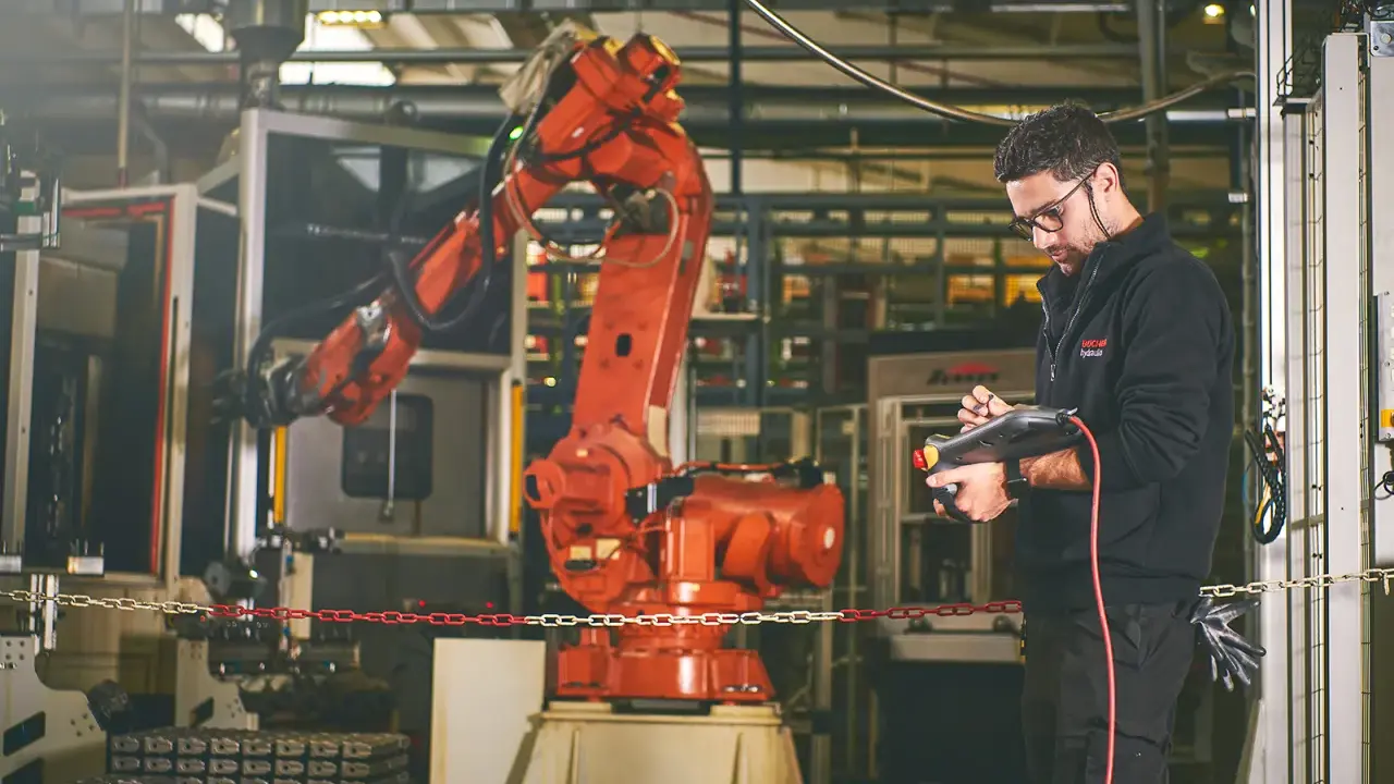 Un disegnatore meccanico opera un braccio robotico in una fabbrica. Il suo stipendio è ben meritato per la precisione richiesta.