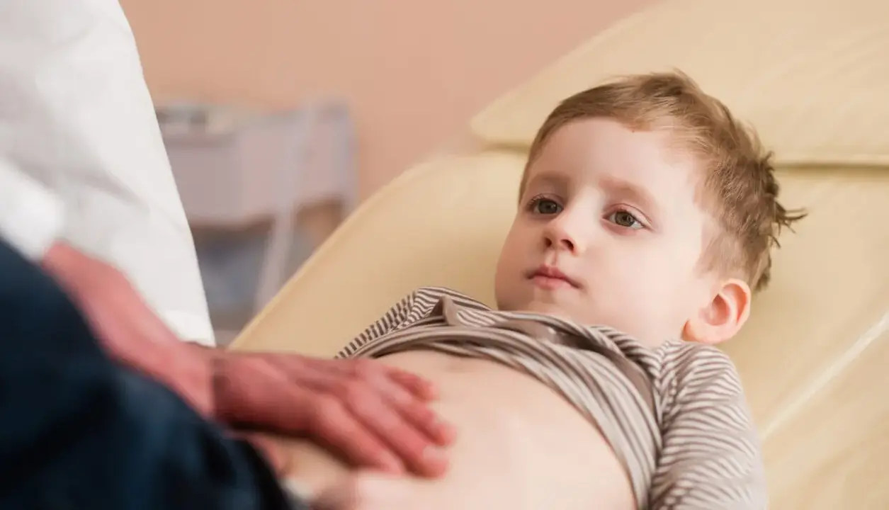 Un bambino viene visitato per sospetto neuroblastoma. Il medico gli tocca delicatamente l'addome.