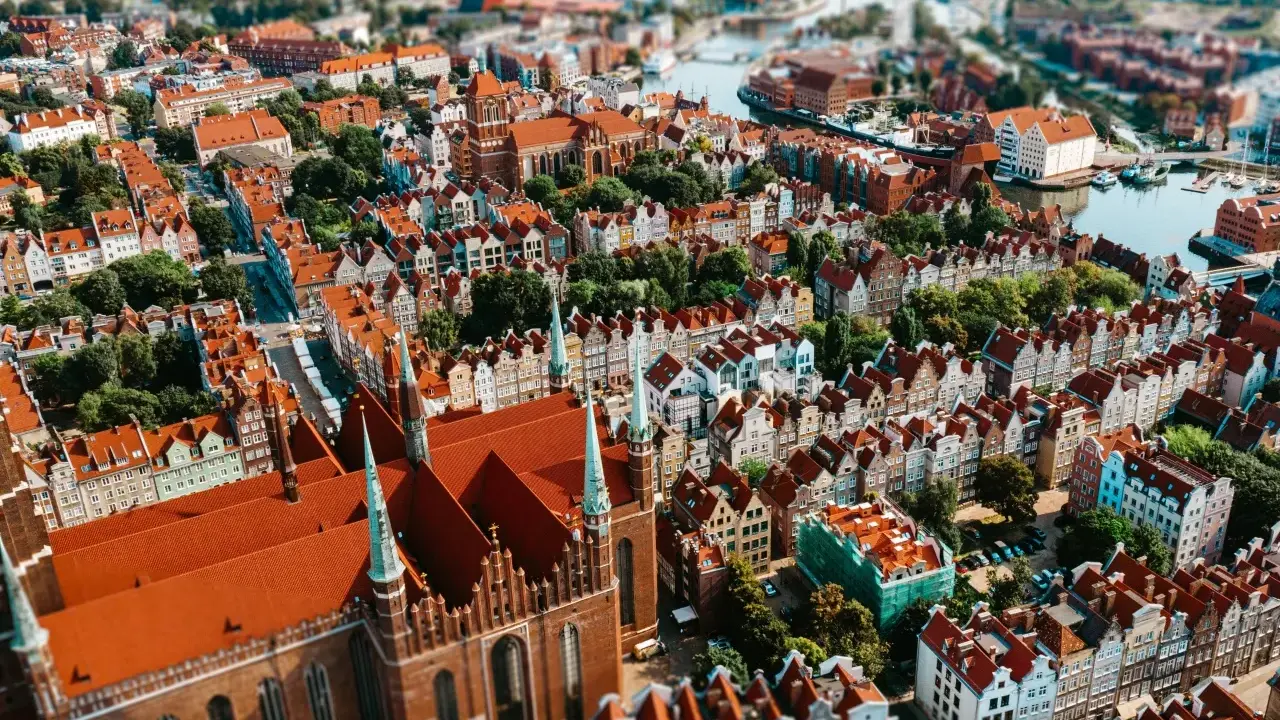 Widok z lotu ptaka na zabytkowe miasto z ceglaną katedrą i kolorowymi kamienicami.