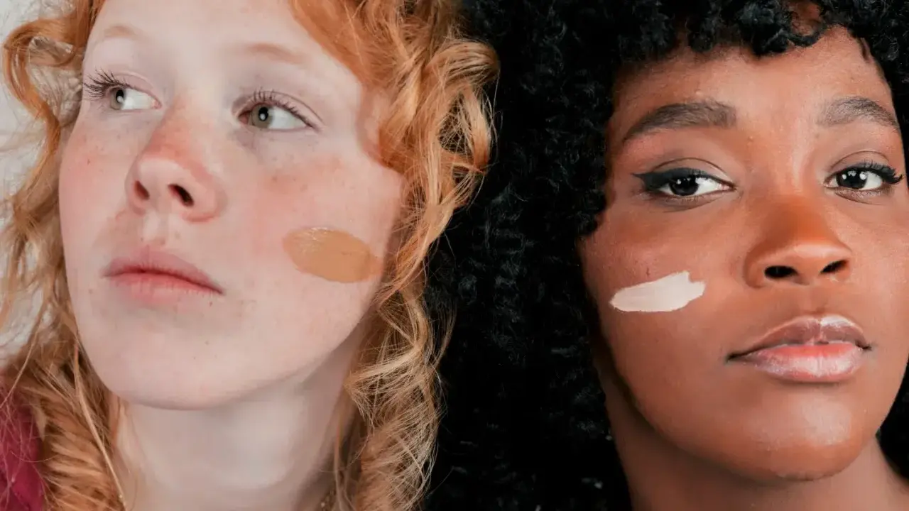 Dos mujeres, una pelirroja pecosa y otra de piel oscura, muestran diferentes tonos de piel con muestras de maquillaje.