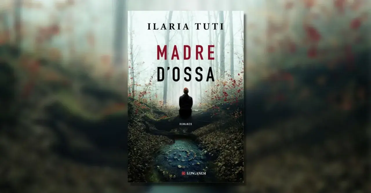 Copertina del romanzo "Madre d'ossa" di Ilaria Tuti. Una figura solitaria siede in un bosco nebbioso, vicino a un ruscello.