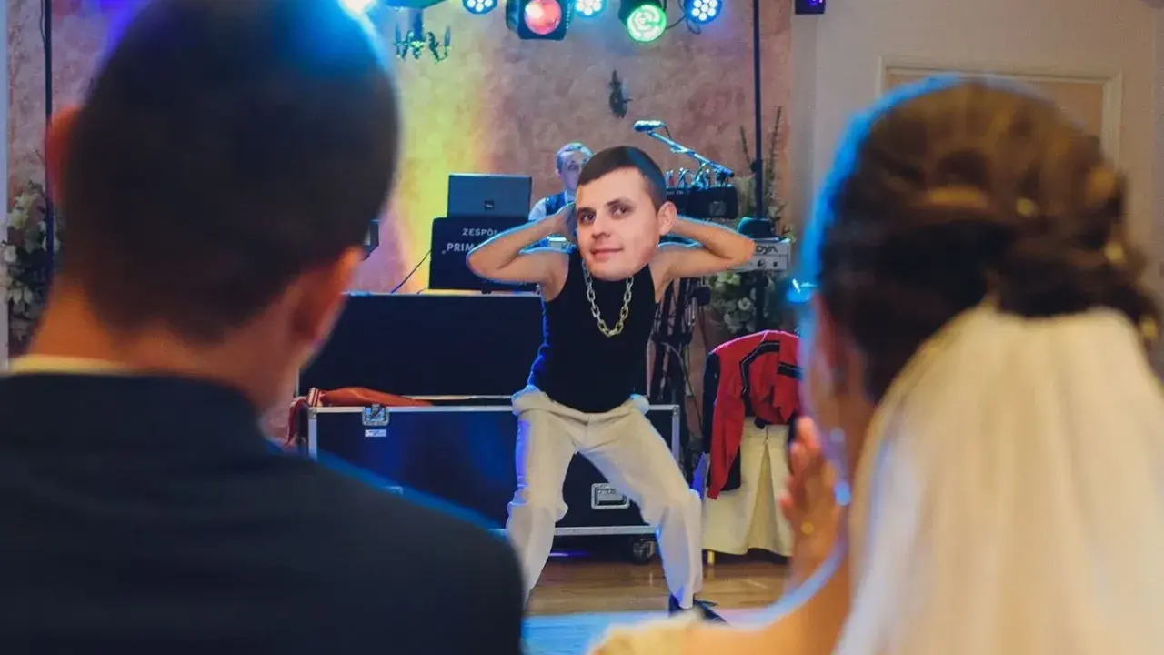 Zabawny pan z twarzą na głowie tańczy na weselu, tworząc nowoczesne zabawy na oczepiny.