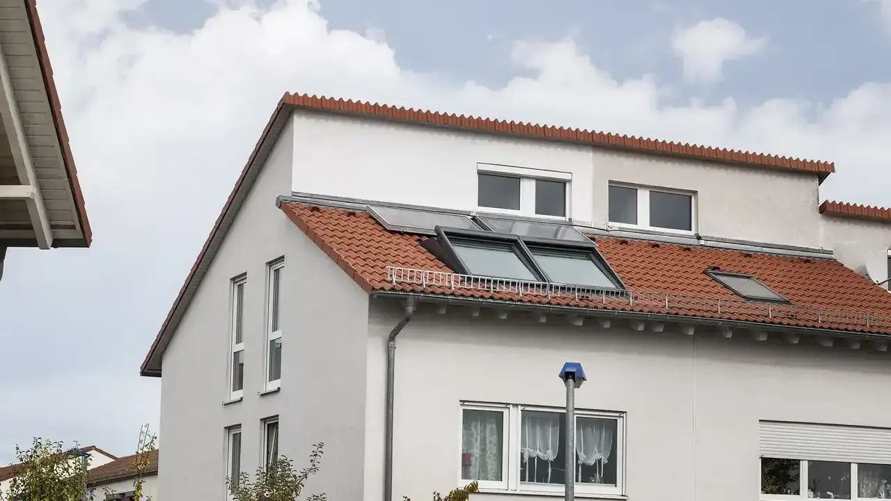 Ein Haus mit roten Ziegeln und Dachfenstern. Das Dach ist ein Pultdach, das nach einer Seite abfällt.