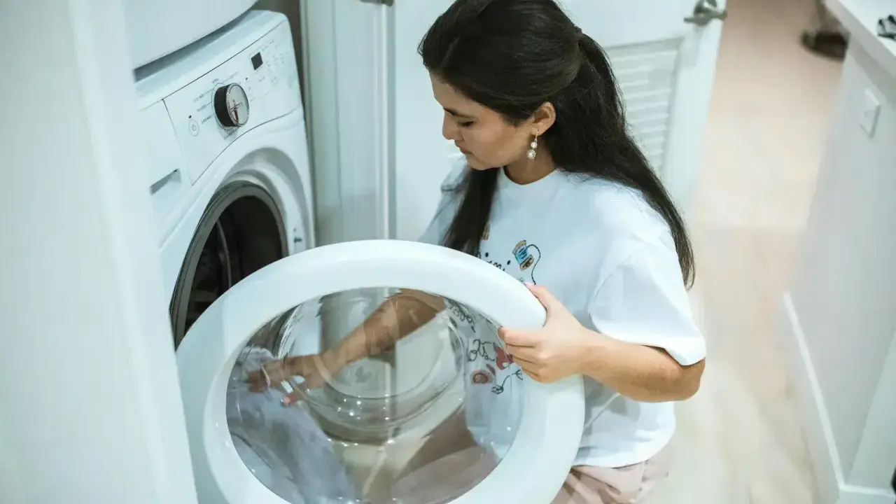 Une femme vérifie le tambour de sa machine à laver, craignant un siphon à machine à laver bouché.