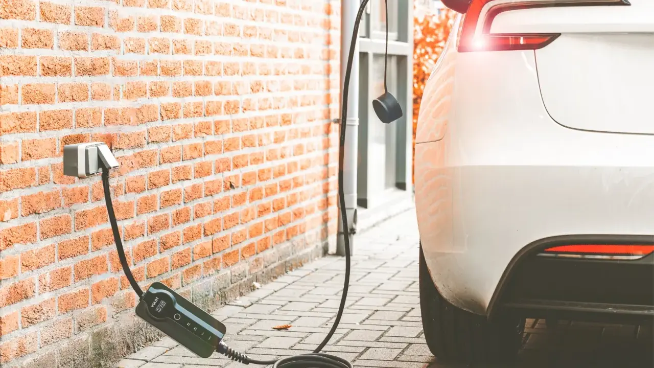 Cargando coche eléctrico a 16 amperios. El cable se conecta a la pared y al vehículo blanco.