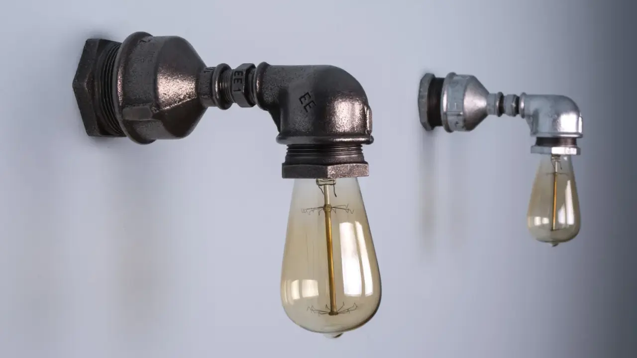 Dwie industrialne lampy z rurek, jedna większa, ciemniejsza, druga mniejsza, jaśniejsza, obie z żarówkami Edisona.