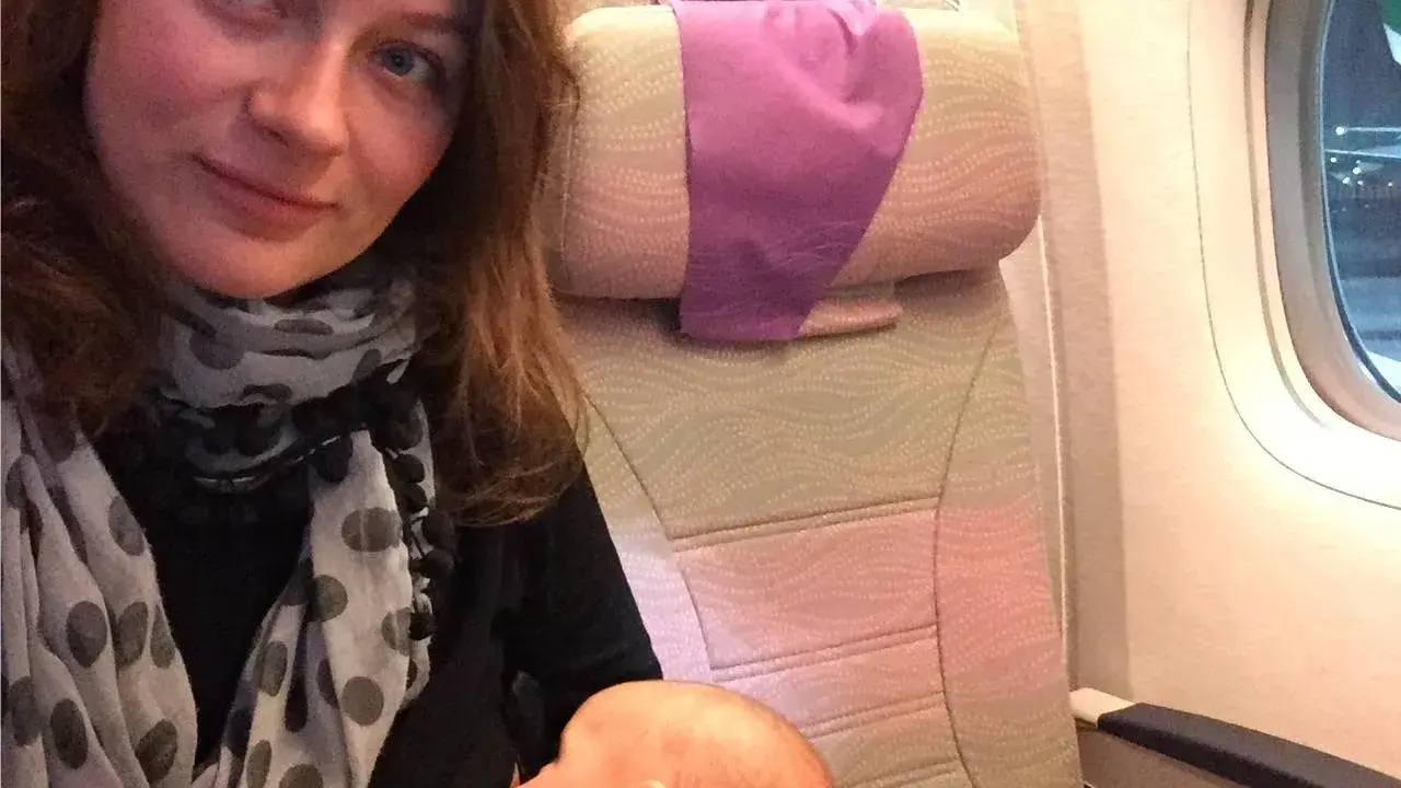 Kobieta karmi niemowlaka podczas lotu samolotem.
