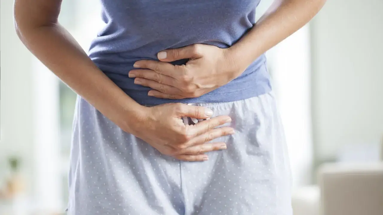 Kobieta trzyma się za brzuch, cierpiąc z powodu bólu menstruacyjnego nie do zniesienia.