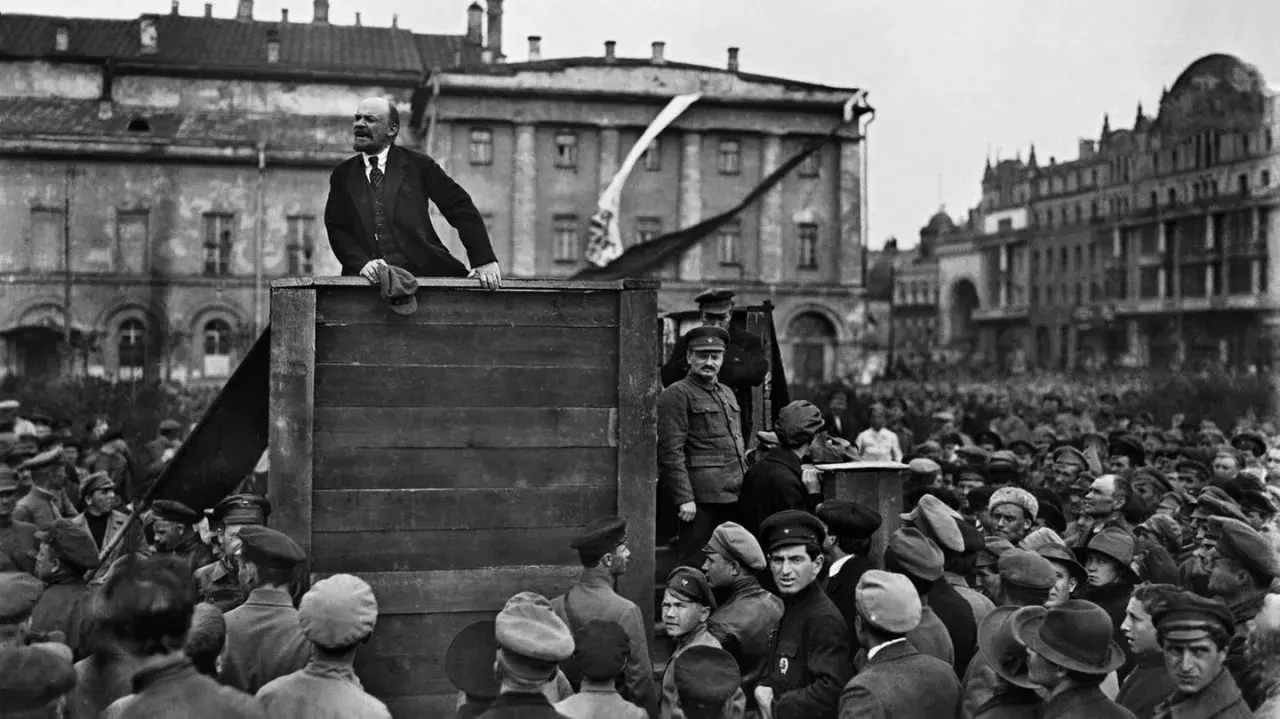 Lenin spricht von einer improvisierten Bühne zu einer großen Menschenmenge. Die Szene wirkt wie eine "revolution von oben", die das Volk mobilisiert.