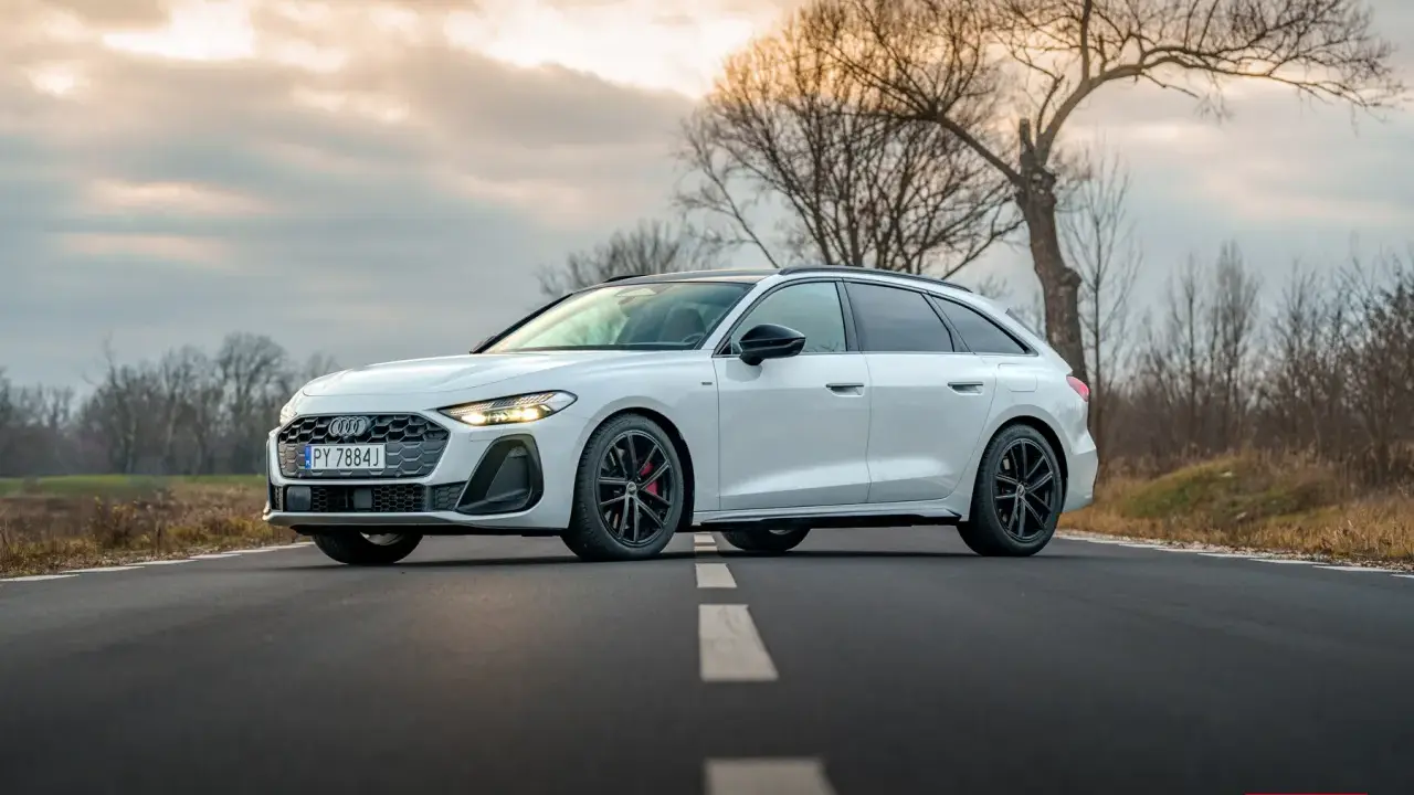 Białe Audi A5 Avant 2025 na drodze, z drzewami w tle.