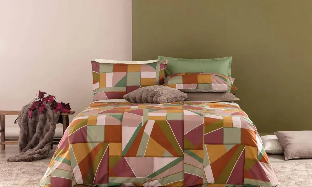Un letto con copripiumino geometrico dai colori caldi e terrosi. Un perfetto abbinamento colori camera da letto per un tocco moderno e accogliente.