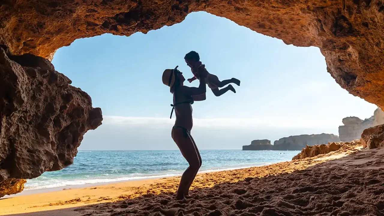 Madre levanta a su bebé en una cueva en el Algarve. Un día perfecto de algarve con niños.