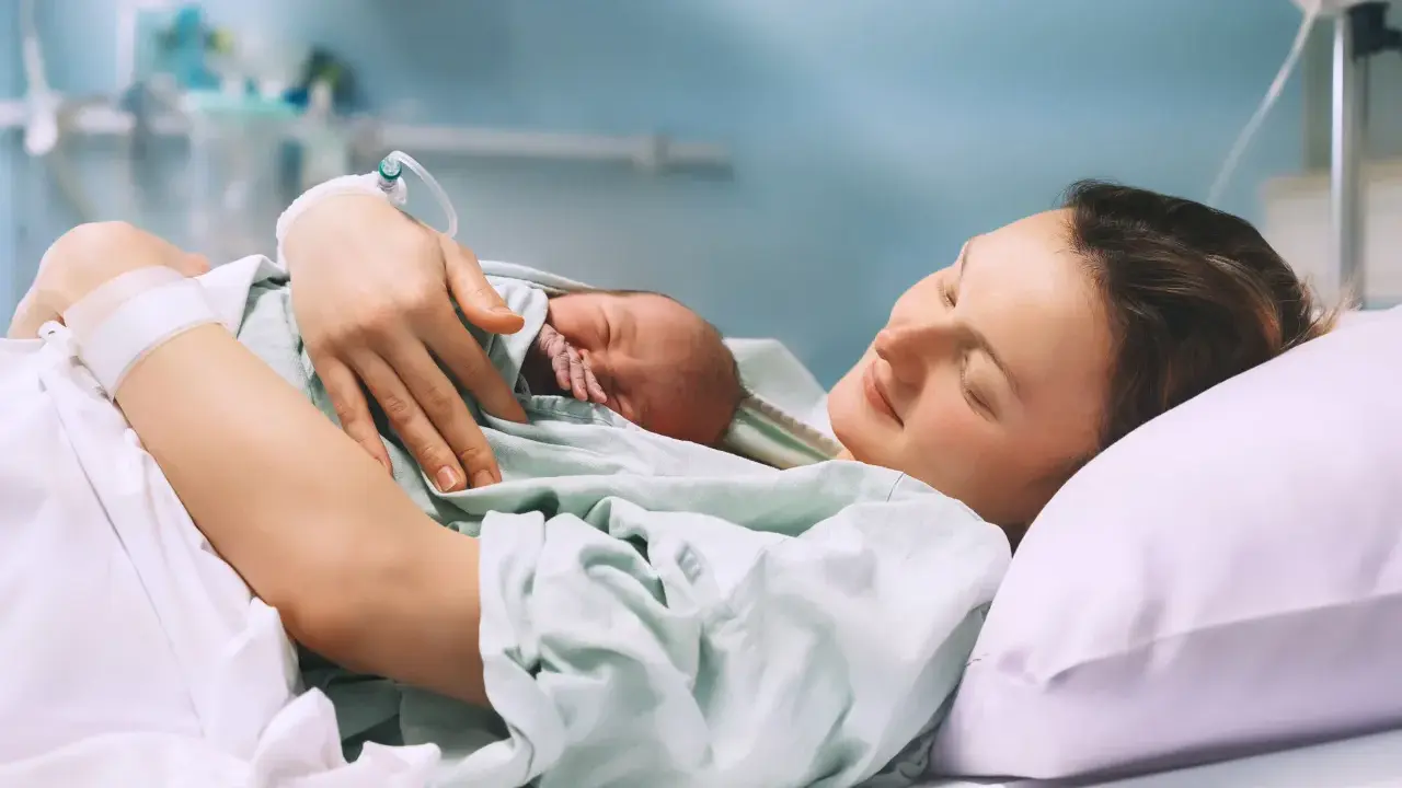 Szczęśliwa mama tuli noworodka po porodzie, czując ulgę po znieczuleniu.
