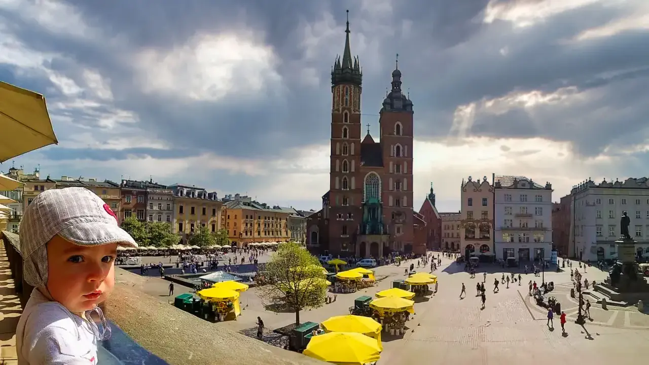 Dziecko na tle Rynku Głównego w Krakowie. To jedno z fajnych miejsc w Krakowie dla młodzieży, pełne życia i zabytków.
