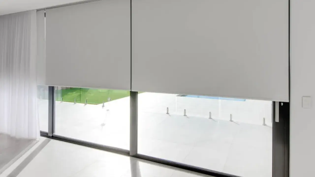 Elegantes persianas enrollables grises ofrecen soluciones para ventanas con mucho sol, bloqueando el deslumbramiento y el calor.