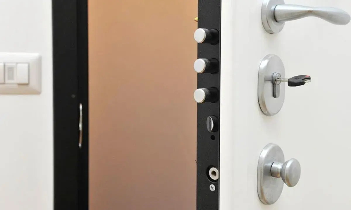 Detalle de una puerta de seguridad con varios tipos de cerraduras y un cerrojo con llave.