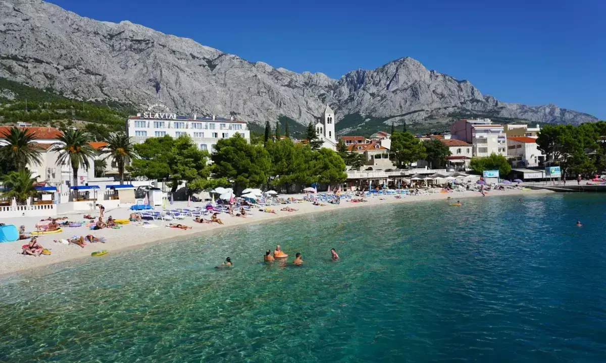 Słoneczna plaża w Baška Voda, z turkusową wodą i górami w tle. To idealne miejsce na relaks i odkrywanie atrakcji.
