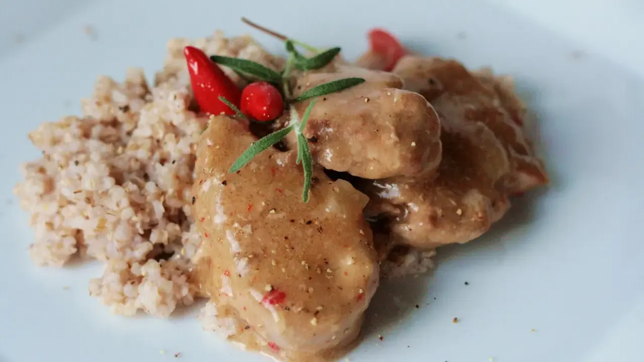 Polędwiczki wieprzowe w sosie własnym, danie Ani gotuje, podane z kaszą i ozdobione papryczką chili i rozmarynem.