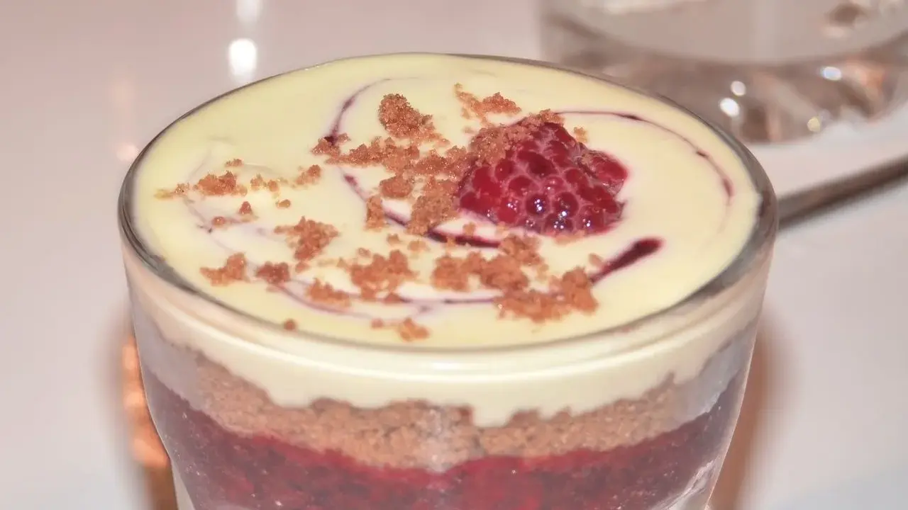 Verrine speculoos framboise : couches de biscuits émiettés, compotée de framboises et crème onctueuse, surmontée d'une framboise fraîche et miettes de spéculoos.