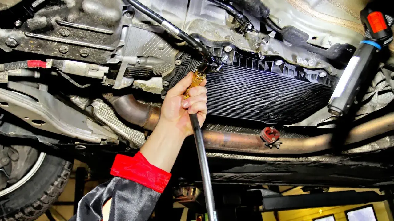 Mechanik wykonuje wymianę oleju w skrzyni automatycznej, używając specjalistycznego sprzętu do serwisu.