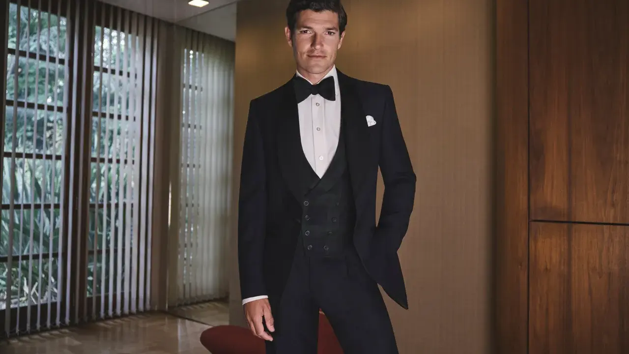 A man in a tuxedo, embodying the perfect gala dinner dress code male attire, stands confidently.