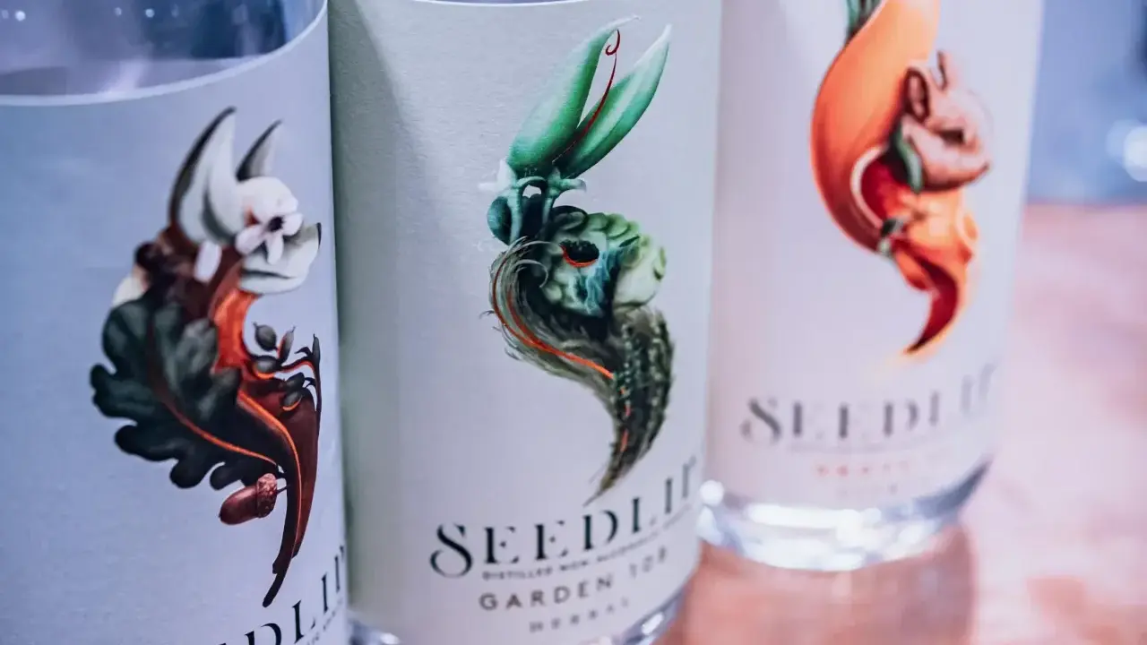 Drei Flaschen Seedlip alkoholfreien Gin mit kunstvollen Etiketten, die fantasievolle Tiere und Pflanzen zeigen.