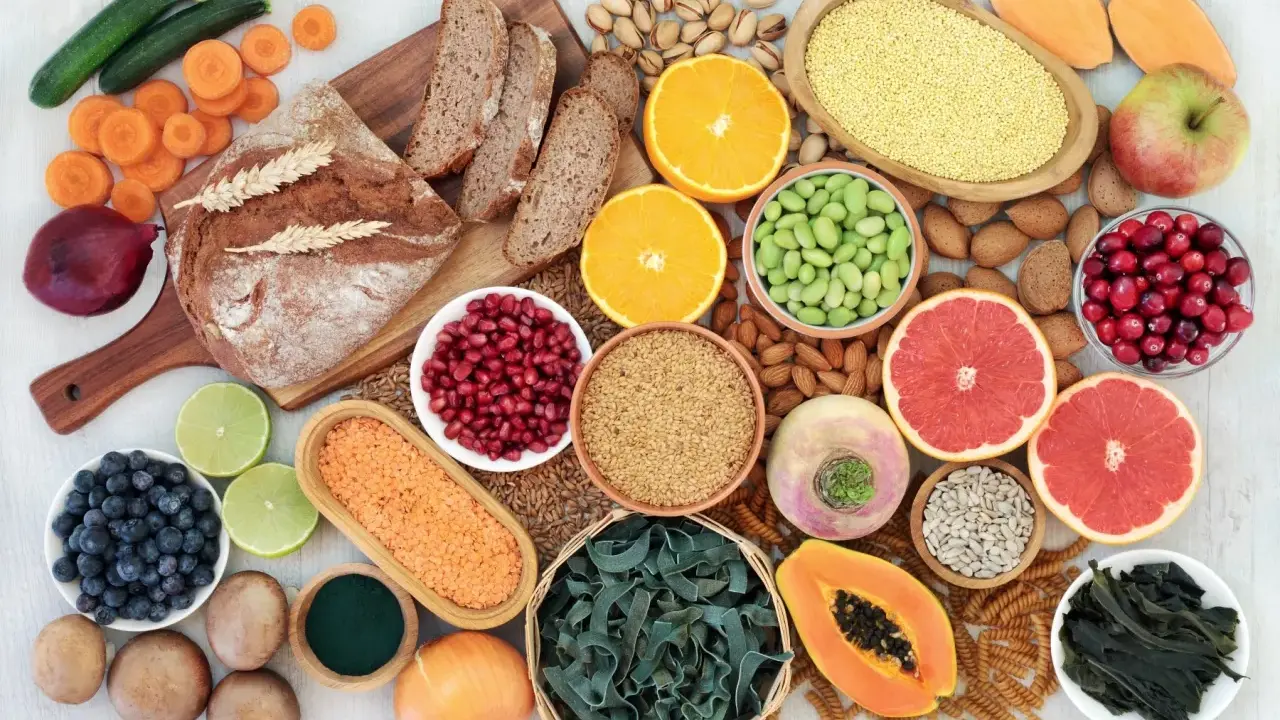 Vielfalt an ballaststoffe produkten: Vollkornbrot, Linsen, Beeren, Nüsse, Obst und Gemüse für eine gesunde Ernährung.