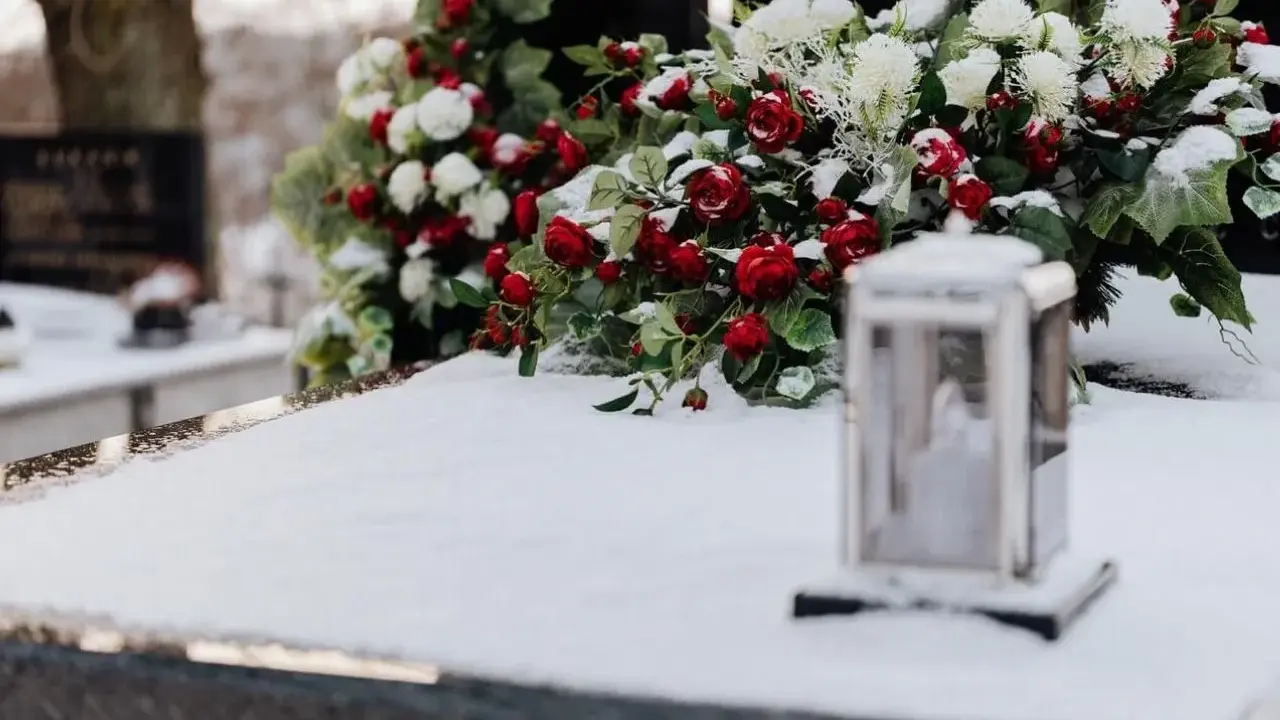 Wieniec dla taty: czerwone róże i białe kwiaty na śniegu, obok lampion.