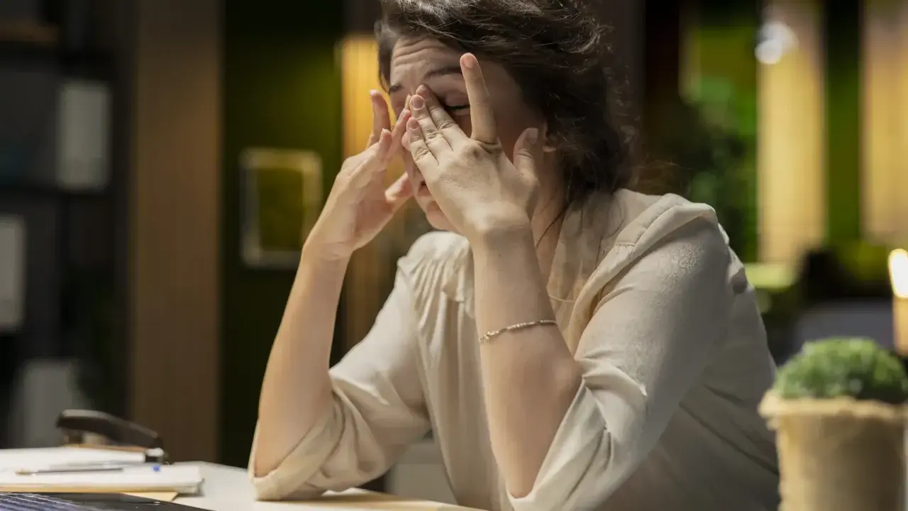 Eine Frau reibt sich erschöpft die Augen, die Arbeit am Laptop ist zu viel. Ich kann nicht mehr.