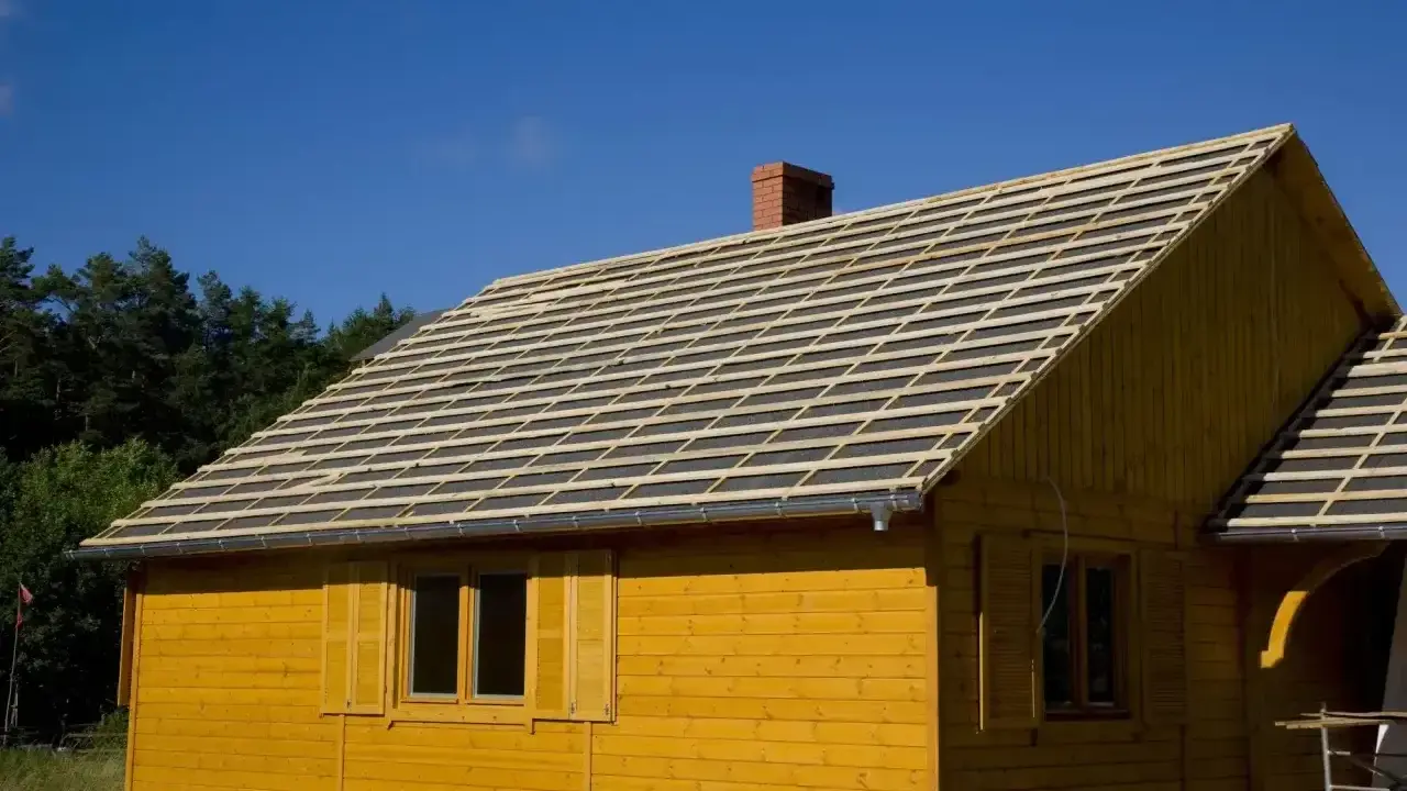 Żółty domek z widocznym pełnym deskowaniem dachu, przygotowanym pod pokrycie.