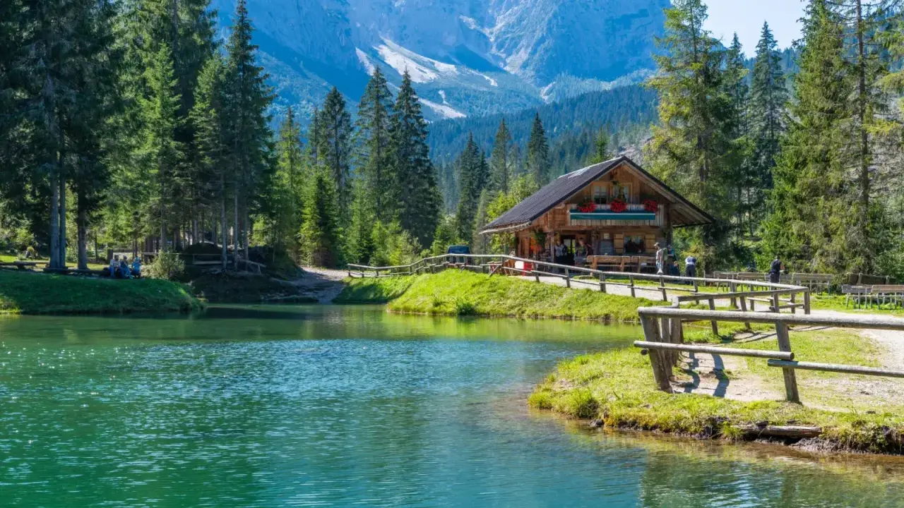 Rifugio alpino in Italia, con lago cristallino e montagne sullo sfondo. Perfetto per una vacanza in montagna Italia.
