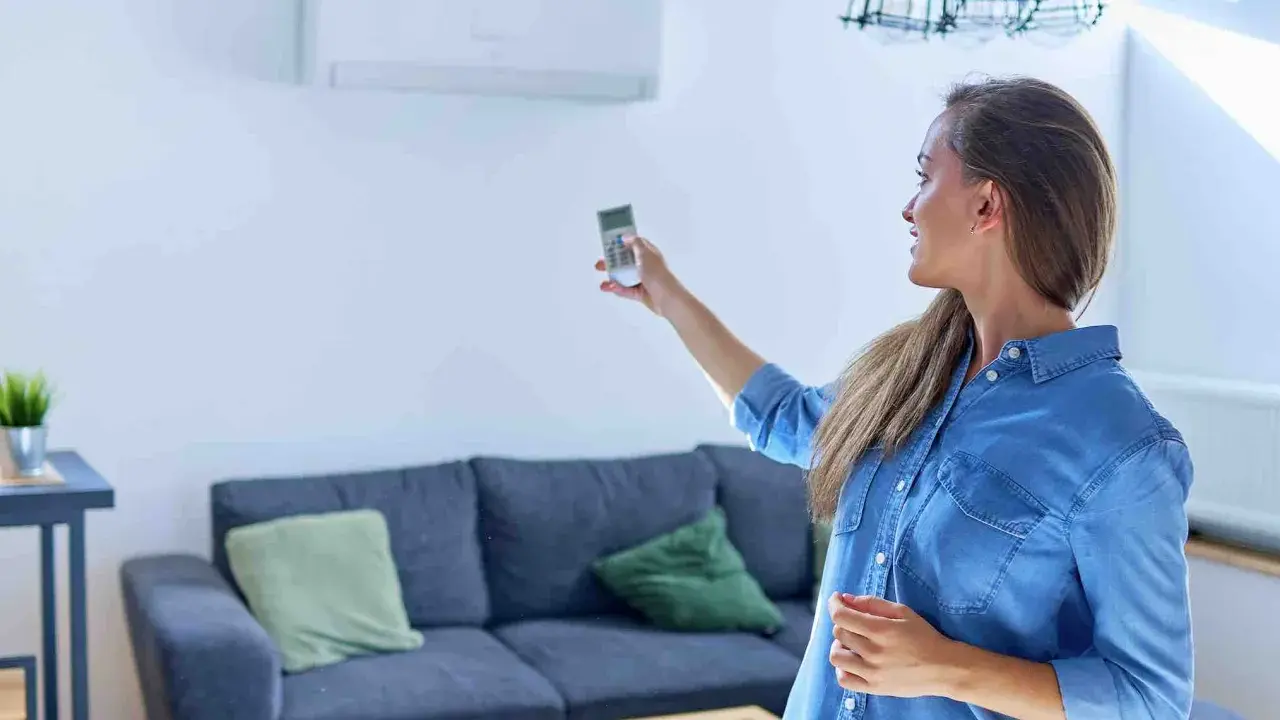 Mujer ajustando el sistema de climatización con un control remoto.