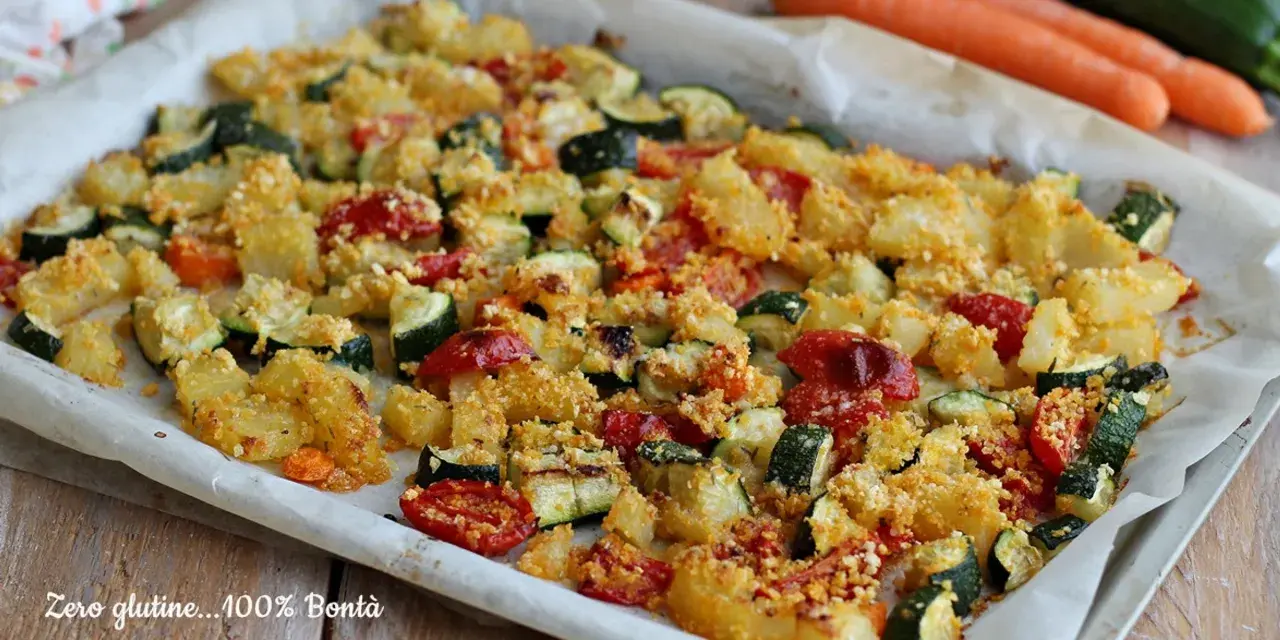 Un vassoio di verdure al forno, con patate, zucchine e pomodorini, condite con pangrattato dorato.