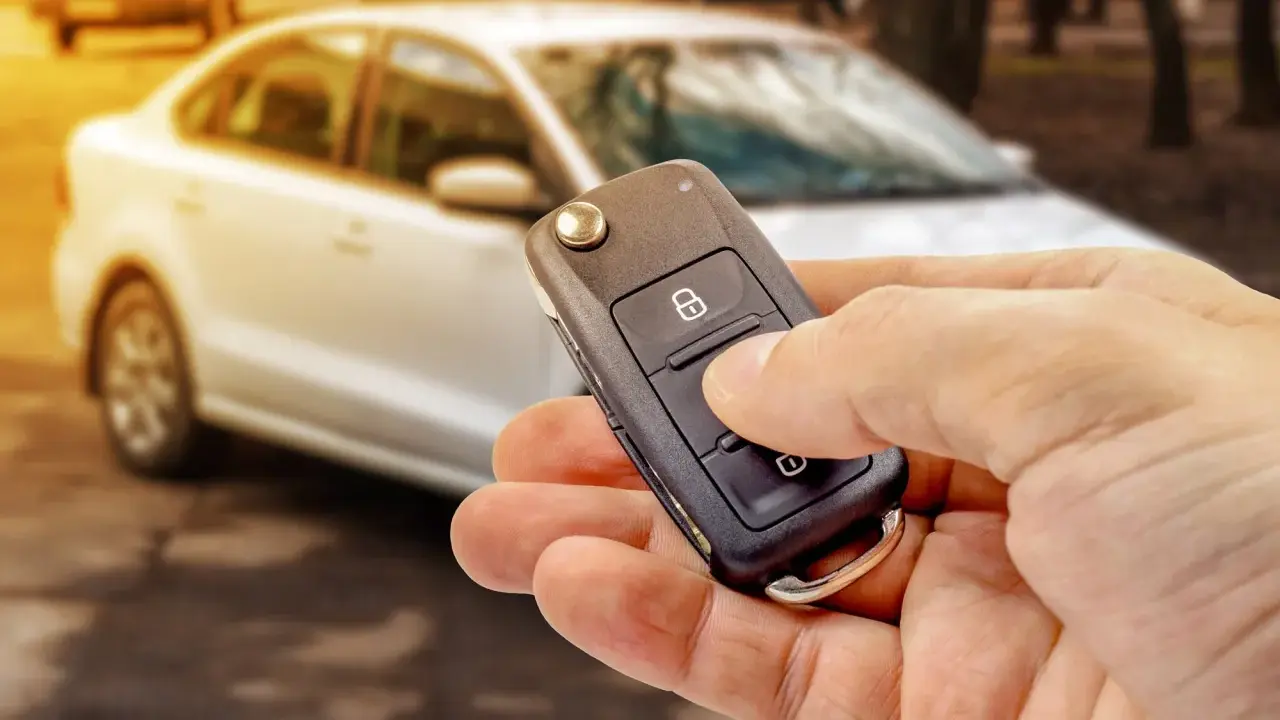 Dłoń trzyma kluczyk samochodowy z przyciskiem blokady. Czy to immobilizer? To system zabezpieczający auto przed kradzieżą.