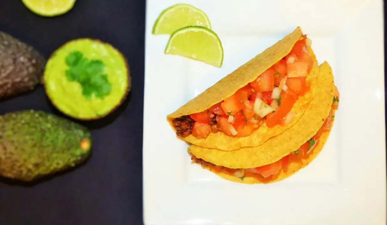 Pyszne meksykańskie tacos przepis na talerzu, z awokado i limonką w tle. Idealne na szybki obiad!