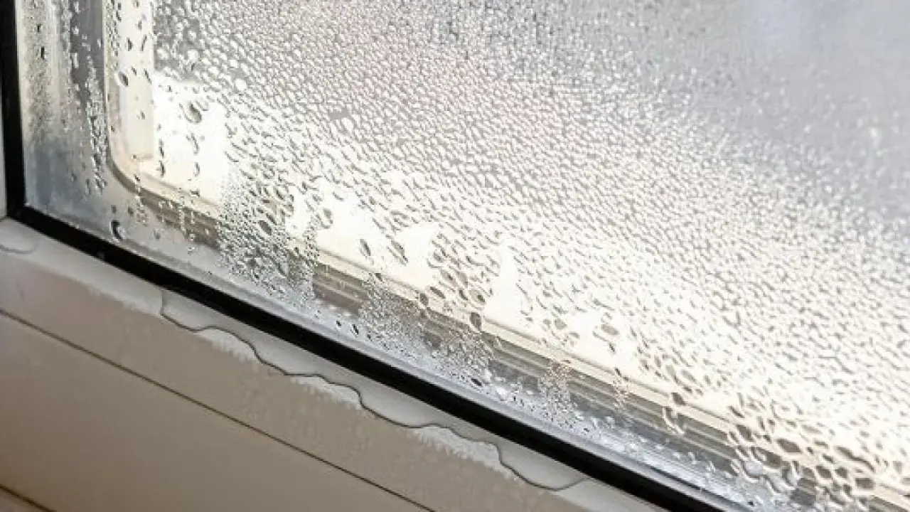 Ventana con gotas de agua, un claro ejemplo de condensación. El vapor de agua se ha adherido al cristal, formando pequeñas gotas que resbalan por el marco.