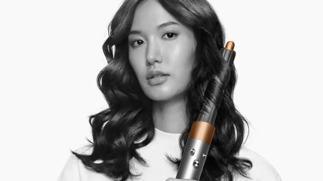Frauenhaar wird mit einem Airwrap-Lockenstab zu perfekten Wellen geformt.