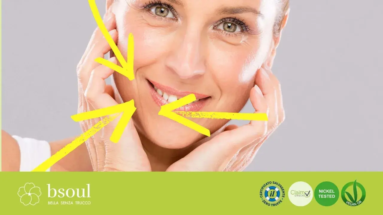 Primo piano di un volto femminile con rughe d'espressione, evidenziate da frecce gialle. Il trucco leggero esalta la bellezza naturale.