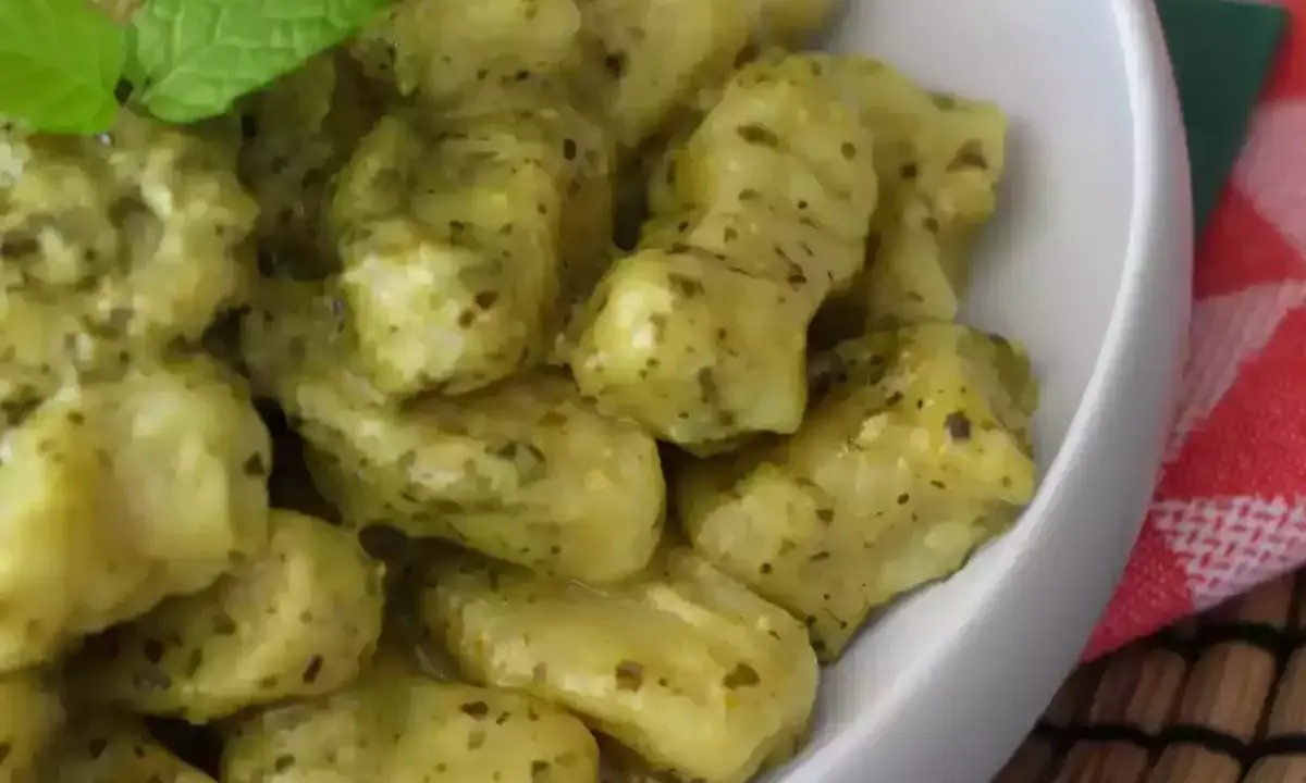 En skål med krämig italiensk gnocchi med pesto, toppad med färsk mynta. Ett perfekt italiensk gnocchi recept för en snabb och god middag.