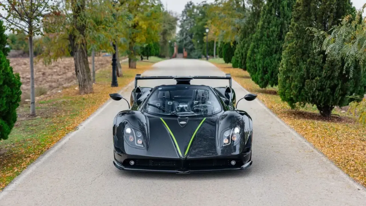 Czarny Pagani Zonda z zielonym akcentem na masce, zaparkowany na alei. Jego cena jest astronomiczna.