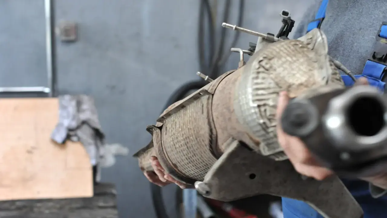 Mechanik trzyma zużyty filtr DPF, przygotowując go do czyszczenia.
