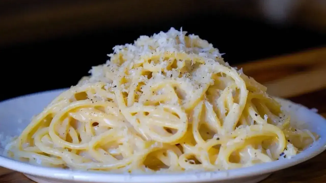 Pyszne cacio e pepe, czyli spaghetti z serem i pieprzem, posypane startym parmezanem.