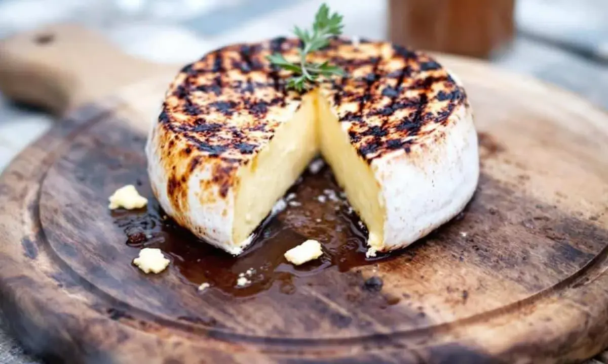 Camembert au barbecue, lait cru ou pasteurisé, grillé à la perfection sur une planche en bois, avec une touche de persil.