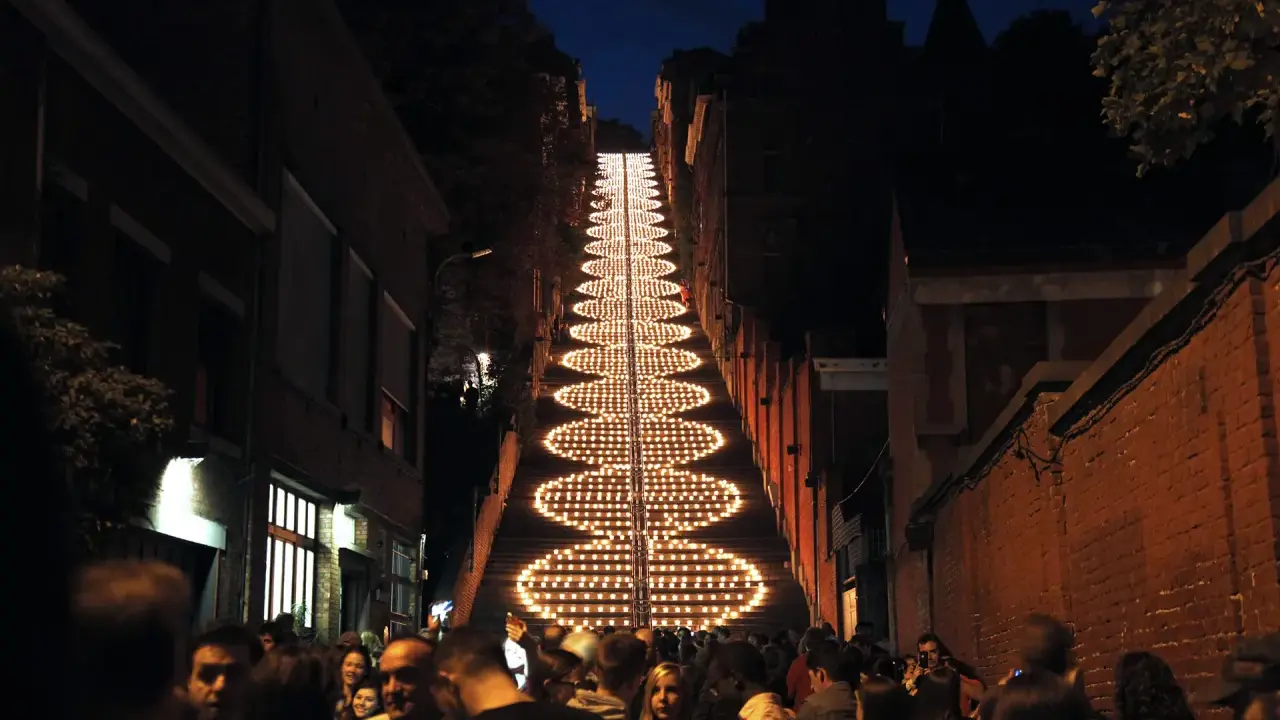 Beleuchtete Treppe in Büren bei Nacht, umgeben von Menschen und Gebäuden.
