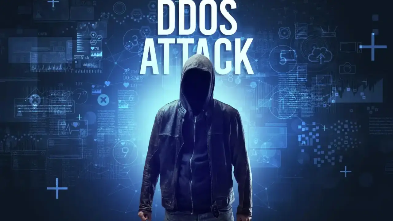 Anonimowa postać w kapturze na tle cyfrowych danych. Wielki napis "DDOS ATTACK" wyjaśnia, ddos co to.