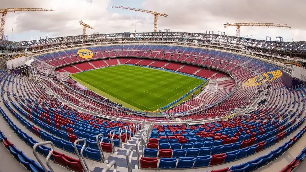 Nowy stadion Barcelony w budowie. Żurawie górują nad trybunami w barwach klubu, gotowymi na przyjęcie kibiców.