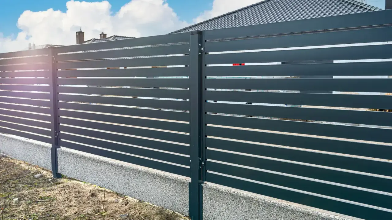 Nowoczesne ogrodzenie z poziomych paneli, osadzone na betonowym cokole. To świetne rozwiązanie co zamiast podmurówki pod ogrodzenie, zapewniające estetykę i trwałość.